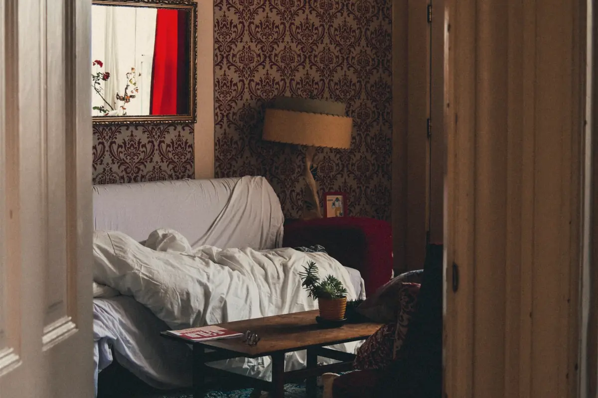 A bedroom seen through a doorway with patterned wallpaper