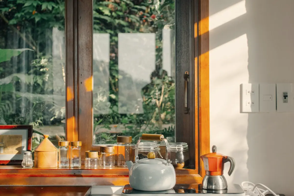 A kitchen counter with a kettle and morning light through a window