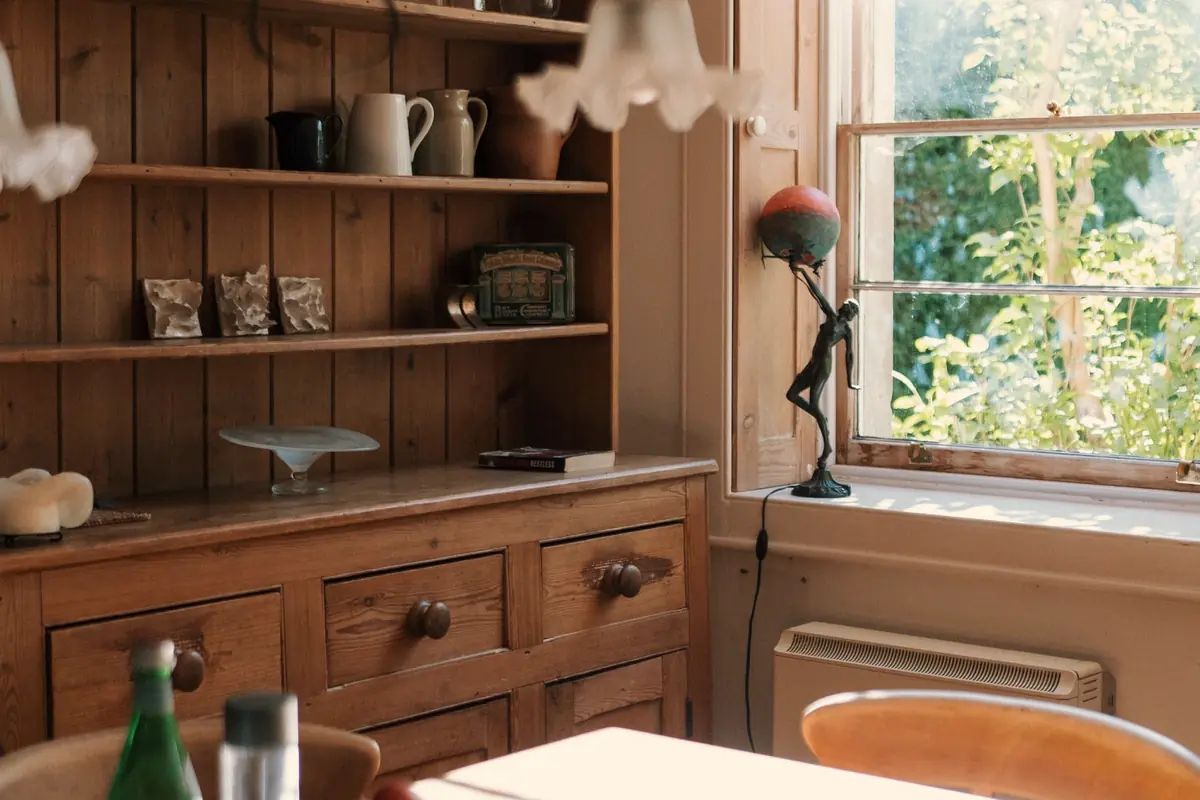 A kitchen with wooden cupboards, open shelves and a window