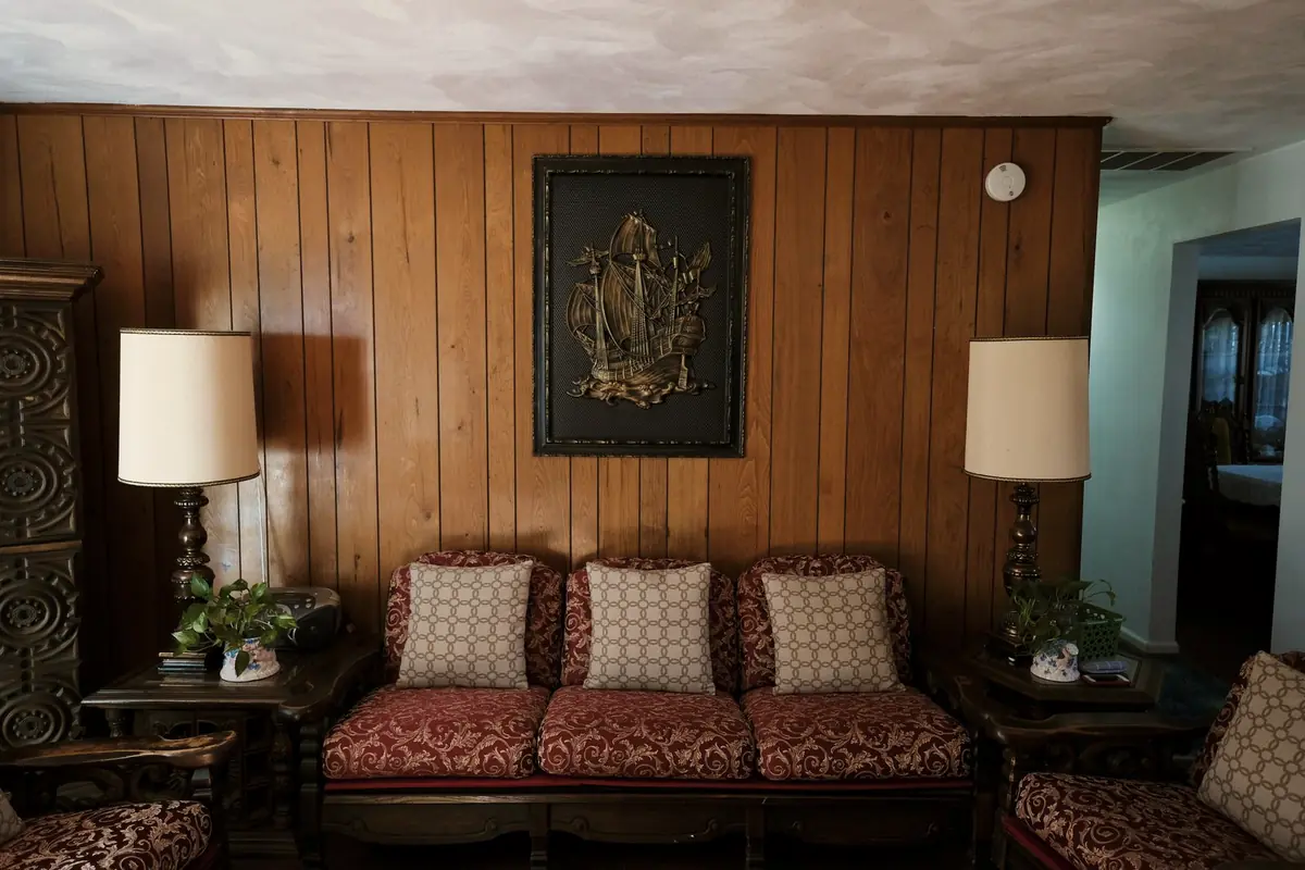 A lounge with wood panelled walls, a sofa and two lamps